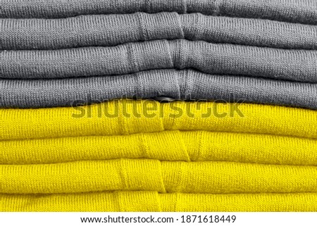 Stack of clothes trend colors 2021 illuminating yellow and gray.