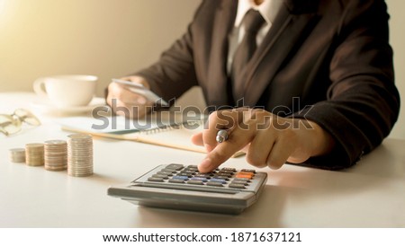 Account management and money saving concept, a close-up of a woman using a calculator to produce accounting work reports.Soft focus