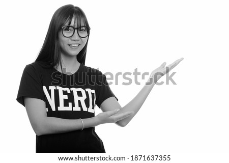Young happy Asian nerd teenage girl smiling and showing something