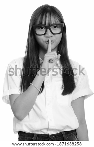 Young cute Asian teenage girl with finger on lips