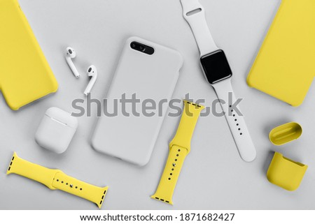 Stylish smart watch, phone, earphones and cases on gray background Royalty-Free Stock Photo #1871682427