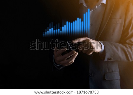 Business man holding holographic graphs and stock market statistics gain profits. Concept of growth planning and business strategy. Display of good economy form digital screen