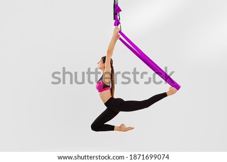 Sporty woman practicing fly yoga over white background. Aero fly yoga concept. Copy space.