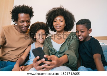 Family taking selfie together with phone at home.