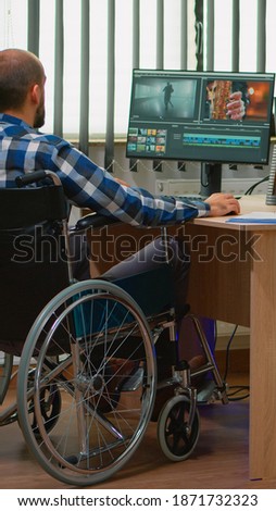 Team of videographers working at video project creating content, man blogger sitting in wheelchair in modern company office. Disabled freelancer editing footage postproduction in studio.