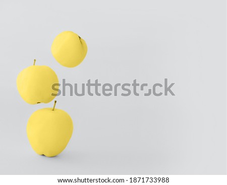 Illuminating Yellow apples on a Ultimate Gray background in levitation in trendy 2021 new colors. bright juicy fruits. Color of the Year 2021. Design element for prints, backgrounds, template.