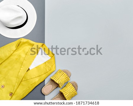 Female jacket and stylish slippers in trendy illuminating yellow colour on contrast ultimate gray background. Minimalist female outfit. Color of the year 2021. Main color trend. Summer sale concept.