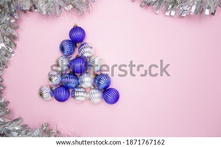 Christmas balls for decorating blue and silver on a pink background in the form of a Christmas tree and a garland. Free space for text, top view. new year.