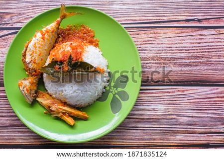 A picture of Ikan Kembung  "asam pedas" with white rice on a wooden background. "Asam pedas" is sour soup made from tamarind, chilli and spices that is popular in Malaysia .