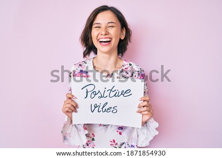 Young beautiful girl holding positive vibes banner smiling and laughing hard out loud because funny crazy joke.  Royalty-Free Stock Photo #1871854930