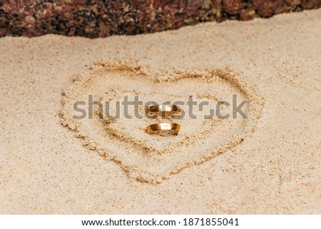 Wedding rings inside a heart of sand on the beach. Honeymoon on Koh Nang Yuan Thailand.