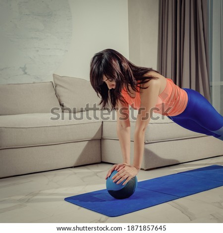 Sporty young woman doing exercise with fitball at home