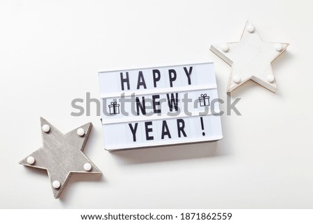 New Year or Christmas composition, flat lay, top view. Light box inscription Happy New Year and wooden star decorations, copy space.