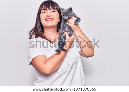 Young beautiful plus size woman smilling happy and confident. Standing with smile on face holding adorable cat over isolated white background