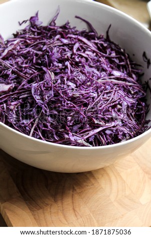 A white bowl with grated red cabbage to pickle.