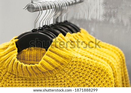 Sweaters hanging on hangers close-up, concept of colors 2021, selective focus