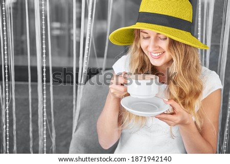 Young woman at cafe. Morning beverage. Two color. Yellow and grey. Person drink breakfast aroma cappuccino. Vacation hat. Copyspace. Hot drink at restaurant
