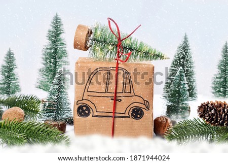 Christmas present with drawn car carrying Christmas tree on the roof in winter scenery with falling snow