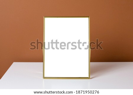 Gold frame copyspace on white table with dark orange wall background