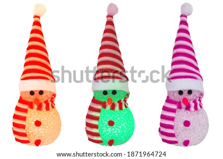 Christmas decoration elements isolated. Close-up of three various colored illuminated happy cute winter snowman with red white striped hat and scarf isolated on a white background. Macro photograph.