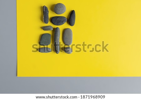 Flat lay in a trendy 2021 new colors. Illuminating Yellow and Ultimate Gray. Color of the Year 2021. Grey sea stones on yellow background.