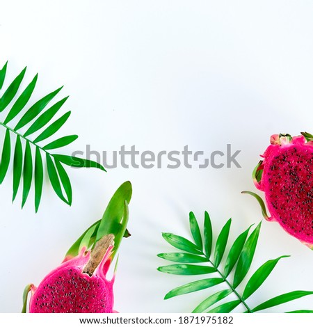 Fresh organic pink dragon fruit, pitaya or pitahaya with pink middle. Trendy top view with palm leaves on white background with text space.