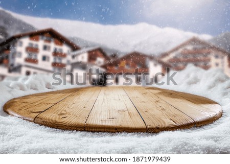 Fresh snow on a wooden table with an alpine view of the mountains