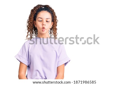 Beautiful kid girl with curly hair wearing casual clothes making fish face with lips, crazy and comical gesture. funny expression. 