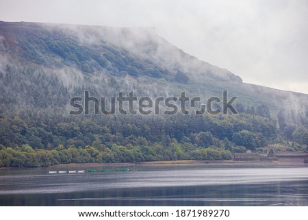 Misty, foggy landscape scenes from Ladybower reservoir in the Peak District National Park, U.K. Mist raising out of the woodland that surrounds the reservoir. Royalty-Free Stock Photo #1871989270