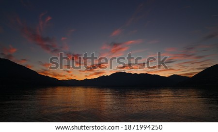 Picturesque sunset over the lake in autumn, with pink, red and orange colored clouds. Very nice picture.