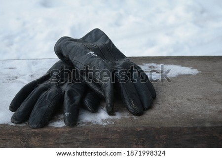 old leather gloves on a bench in the snow