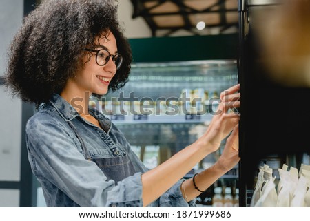 Beautiful smiling 20s female barista using vending machine in cosy coffee shop Royalty-Free Stock Photo #1871999686