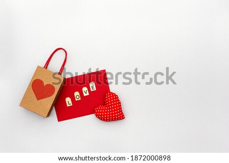 Valentines day layout, red shape of heart with paper bag and envelop with wooden letters on grey background. Copy spase