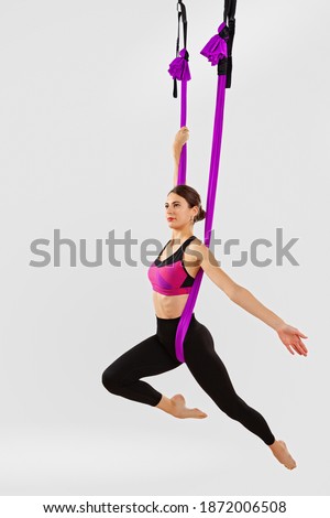 Young slim woman posing aerial yoga on a white isolate. Fly yoga. Sport healthy lifestyle concept. 