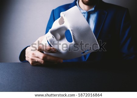 Businessman holding white mask in his hand Royalty-Free Stock Photo #1872016864