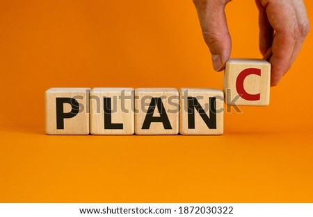 Time to plan C. Wooden cubes with the words 'plan C'. Businessman hand. Beautiful orange background. Business and plan C concept. Copy space.