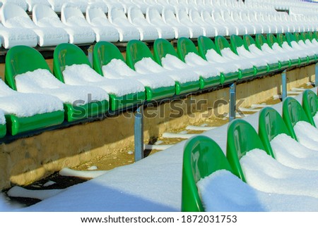 plastic seats in a football stadium covered with snow in winter