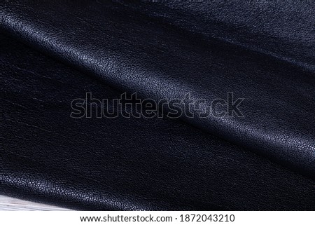 Black dyed natural genuine cow leather folded on a table.
