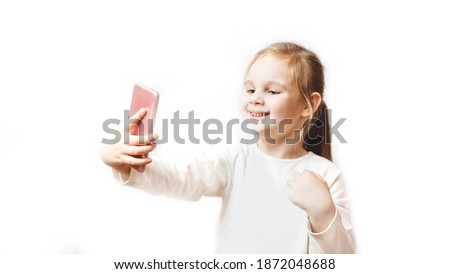 Little caucasian girl makes a selfie photo on a smartphone. Modern wireless technologies and devices concept. white background. Childhood