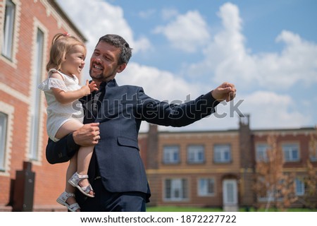 Caring father holds on hands of his little daughter outdoors.