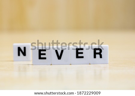 A row of small white plastic tiles, containing the letters forming the word never and ever, to represent the concept of negation, renunciation.