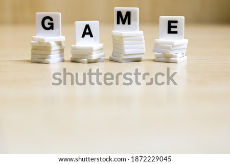 A row of small white plastic tiles, containing the letters forming the word game, to represents the concept of the game.