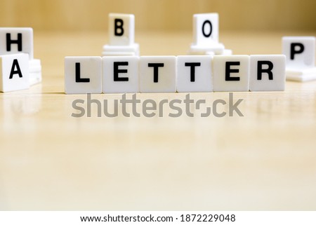 A row of small white plastic tiles, containing the letters forming the word letter, to represents the concept of alphabetic letters.