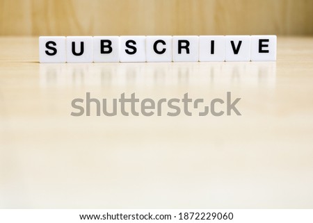 A row of small white plastic tiles, containing the letters forming the word subscrive, to represents the concept of subscribing to something.