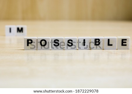 A row of small white plastic tiles, containing the letters forming the word possible, torepresents the concept of possibility, self-esteem and will.