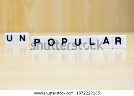 A row of small white plastic tiles, containing the letters forming the word popular, to represents the concept of transformation from unpopular to popular.