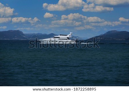 A large yacht of white color float on the water in the background high mountains, cumulus clouds on the blue sky.
