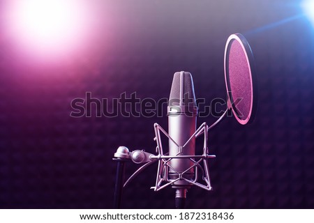 Professional microphone close up in recording studio in neon pink blue lighting, karaoke concept