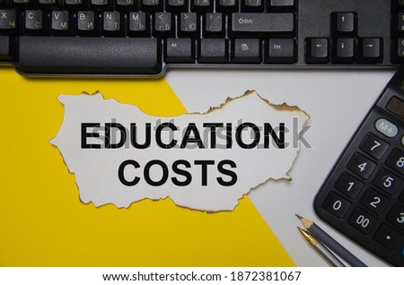 the text education costs is white sheet of paper that lies on a computer keyboard and a yellow and white background. High quality photo