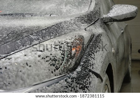 The car body is covered with soap suds to remove dirt. Car wash